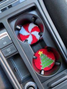 two red and white knitted christmas ornaments in the center console of a car,