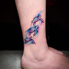 a tattoo on the foot of a woman with blue and pink watercolors turtles