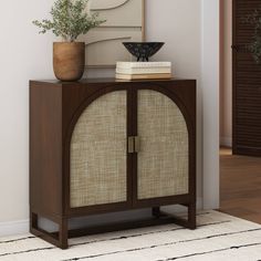 a brown cabinet sitting on top of a wooden floor next to a potted plant