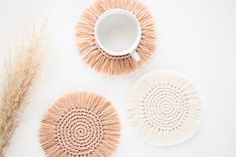 three woven coasters and a coffee cup on a white surface with dried grass in the background