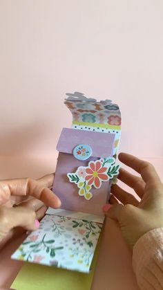 two hands are holding up some cards that have flowers on them and one has a flower in the middle