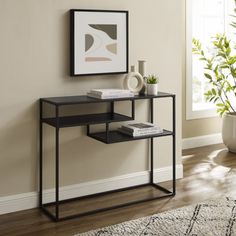 a black metal and glass console table in a living room with a potted plant