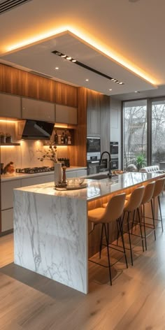 a large kitchen with marble counter tops and bar stools next to an open floor plan