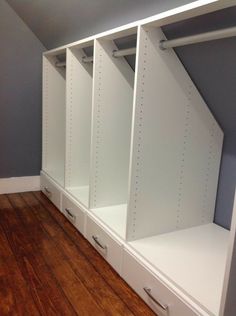 an empty room with some white shelves and drawers on the floor in front of a gray wall