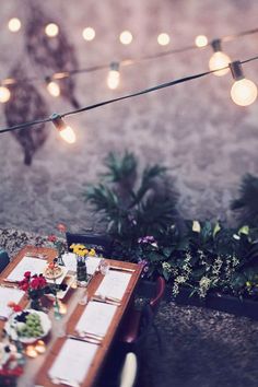 a table with food and candles on it in front of string lights that read la maga de una gurnada de bombilla