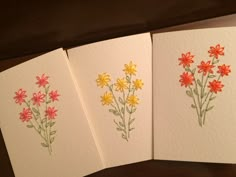 three cards with flowers on them sitting next to each other