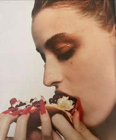 a woman eating a sandwich with red and white toppings