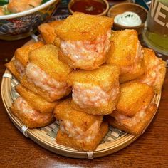 a plate full of fried food on a table with dipping sauces in the background