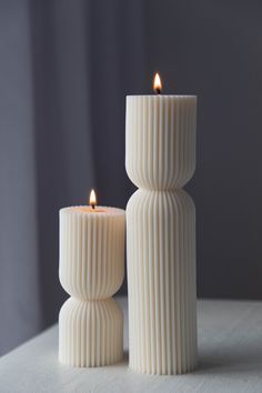 two white candles sitting next to each other on a table