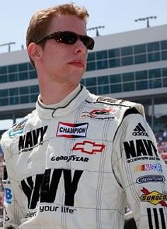 a man standing in front of a crowd wearing sunglasses and a white shirt with black writing on it