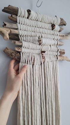 a hand is holding up some driftwood to hang it on the wall with hooks