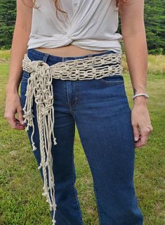 a woman standing in the grass with her hands on her hips wearing a chain belt