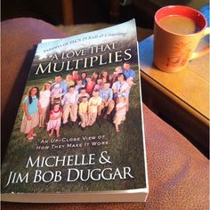 a book sitting on top of a table next to a cup