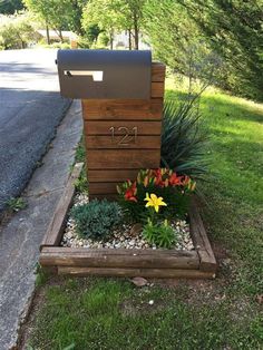 a mailbox sitting in the middle of a flower bed with flowers growing out of it