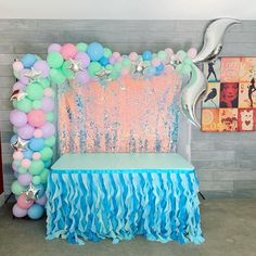 a table with balloons and streamers in the shape of mermaid tails on it next to a chair