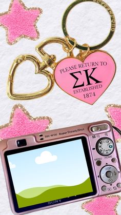 a pink camera with a heart shaped keychain attached to it's front