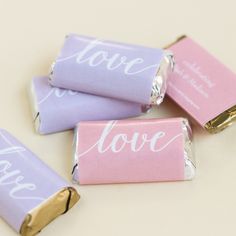 four pink and purple candy bars with love written on the top one is wrapped in gold foil