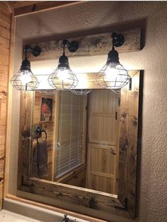 a bathroom mirror with three lights hanging over it