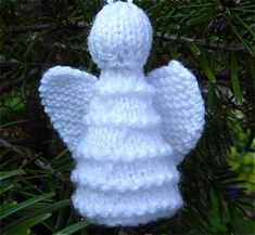 a knit angel ornament hanging from a tree in front of some leaves and branches