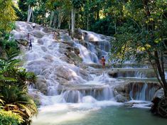 people are standing at the bottom of a waterfall