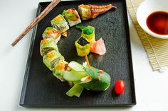 sushi rolls on a black plate with chopsticks