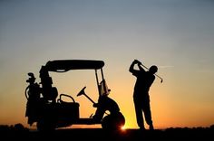 two men are playing golf at sunset in the field with a golf cart behind them