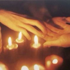 several people holding candles in their hands with one person's hand over the others