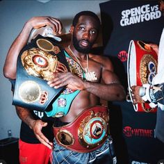 a man standing next to another man holding two boxing belts