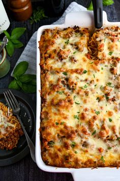 a casserole dish with meat and cheese in it on a table next to a fork