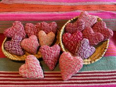 several heart shaped cushions in a basket on a striped tablecloth