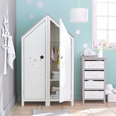 a child's bedroom with white furniture and stars painted on the wall behind it