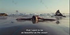 a woman laying on top of a beach next to the ocean with a quote above her