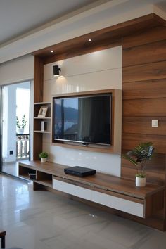 a large flat screen tv mounted to the side of a wooden entertainment center in a living room