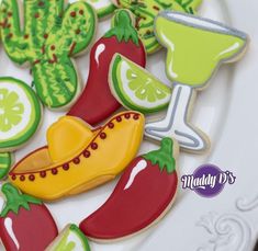 some decorated cookies are on a plate with limes and hotdogs in the background