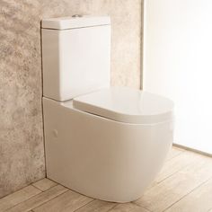 a white toilet sitting in a bathroom next to a wall with a window behind it