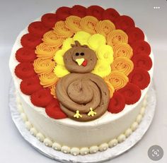 there is a cake decorated like a turkey on the top and red, yellow, and orange swirls around it