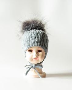 Beautiful hand crocheted baby hat  in grey colour. With long ties to fasten under the chin, earflaps and fluffy artifical big fur pompom, this hat is handmade in high quality soft yarn (100% Merino Superwash). Merino wool is soft and gentle next to baby skin.   Size: 3-6 months - to fit head circumference 15-16" Finished measurements:  Width is 6.5 inches, Height is 5 inches. Please ensure the above measurements are suitable for your baby. Hand wash only at 30o, do not iron. Please make sure tha Knitting Baby Hat, Crocheted Baby Hat, Knitting Baby, Baby Hats Knitting, Crochet Baby Hats, Gender Neutral Baby Clothes, Grey Colour, Baby Hat, Fur Pom Pom