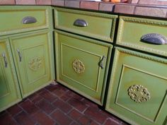 a kitchen with green painted cabinets and brick flooring