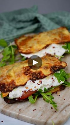 two sandwiches on a cutting board topped with cheese and lettuce