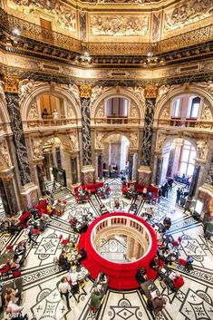 the inside of a large building with many people sitting at tables and standing around it