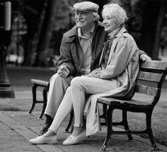 an older couple sitting on a bench in the park together, black and white photograph