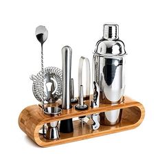 an assortment of kitchen utensils are arranged on a wooden tray with metal cups and spoons