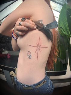 a woman with a knife and compass tattoo on her back shoulder, holding scissors in one hand