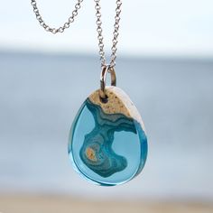 a necklace with a blue and white pendant hanging from it's side on a chain