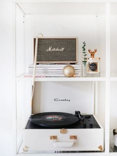 a record player sitting on top of a white shelf