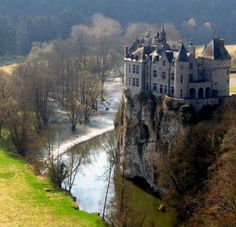 an aerial view of a castle on the side of a cliff next to a river