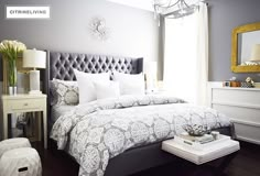 a bedroom with a large bed, chandelier and two chairs in front of the window