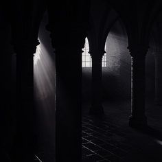 the light shines through the windows in an old building with columns and arches on either side