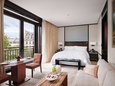 a hotel room with a bed, couch, and coffee table in front of large windows