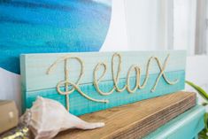 a wooden sign that says relax on top of a shelf next to a potted plant